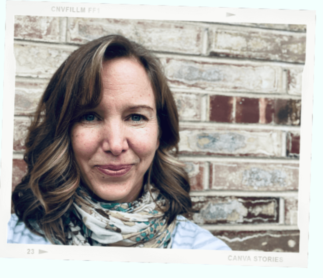 A person with shoulder-length hair wearing a scarf stands in front of a brick wall, smiling slightly, in a photo with a vintage filter.